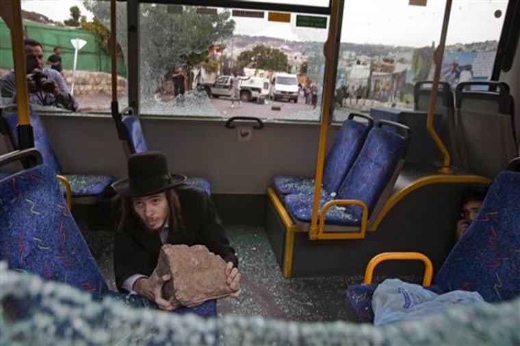 Two ultra-Orthodox Jewish men protect themselves inside a bus from Palestinian rioters outside Jerusalem's Old City on Wednesday.